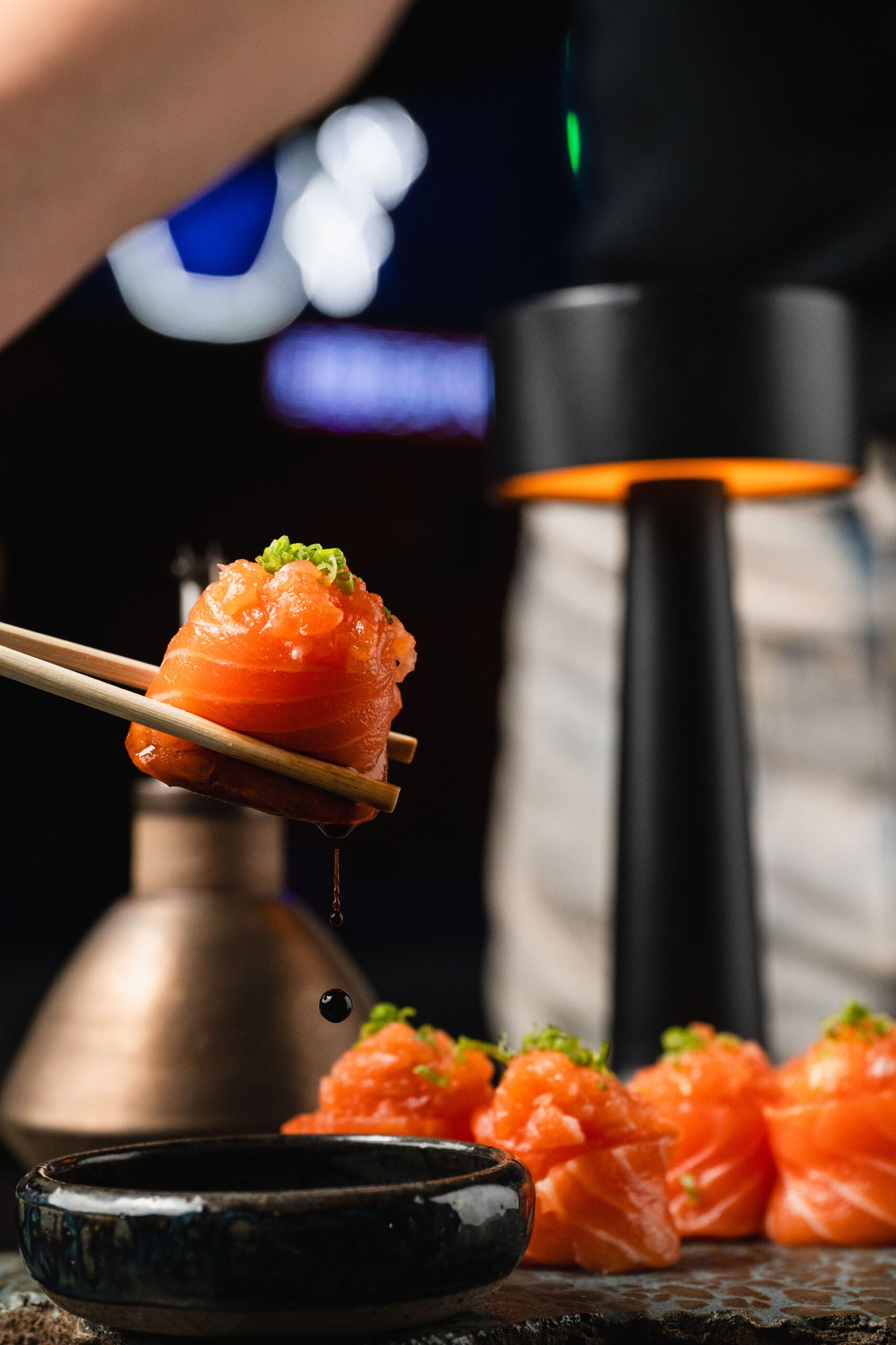 Peça de salmão suspensa por hashis no Yokocho Izakaya