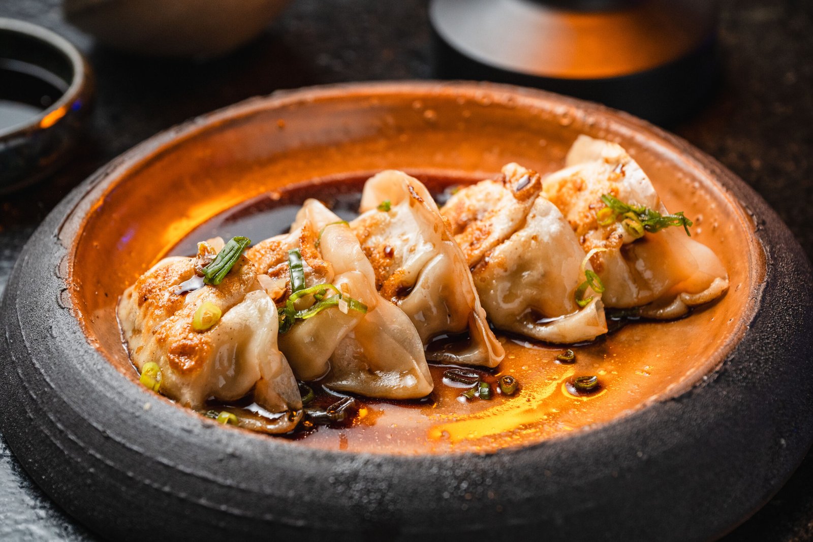 Gyozas douradas servidas em prato artesanal no Yokocho Izakaya